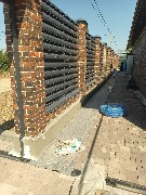 Цоколь забора предварительно обклеен фасадным пенопластом, установлены усиливающие уголки, ведутся армировочные работы